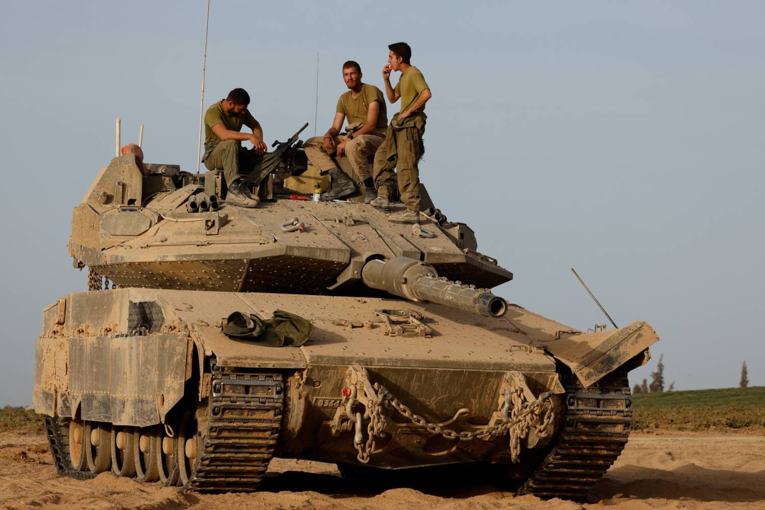 Israeli soldiers eat watermelon on the top of a tank near the Israel-Gaza border
